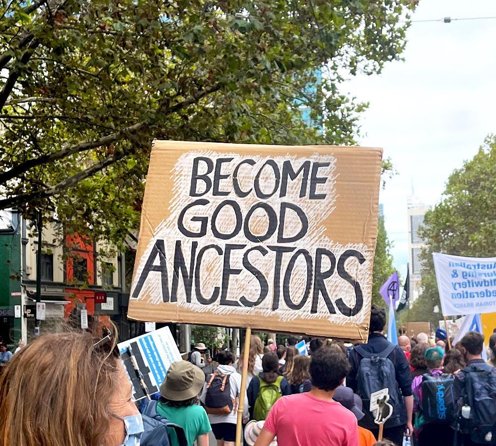 People at Climate march with placard "Become Good Ancestors"