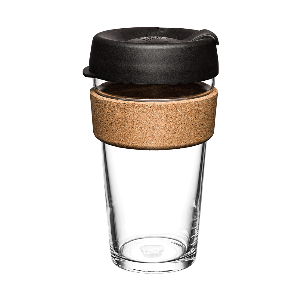 Clear glass reusable coffee cup with black lid and cork sleeve on a white background