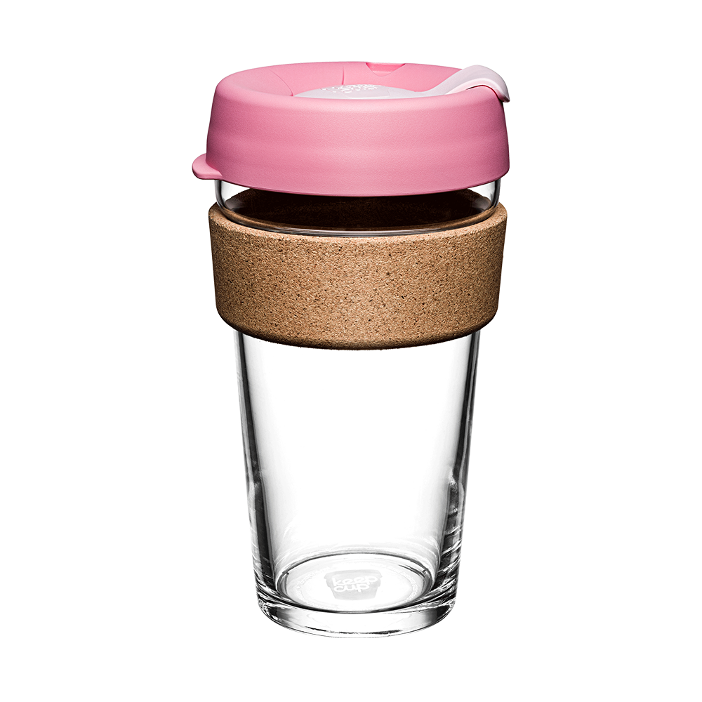 Clear glass reusable cup with pink lid and cork sleeve on a white background