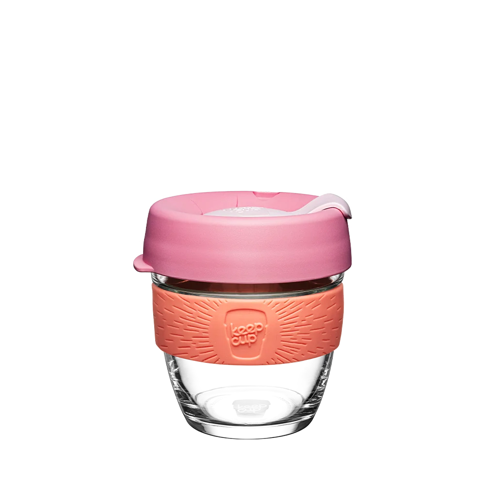 Pink and coral reusable coffee cup with lid on a white background