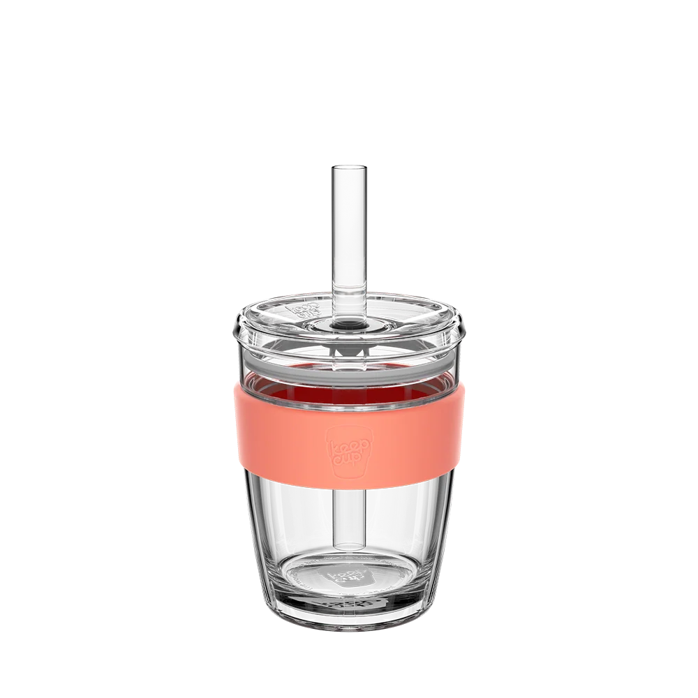 Medium glass tumbler with a coral band and straw on a white background