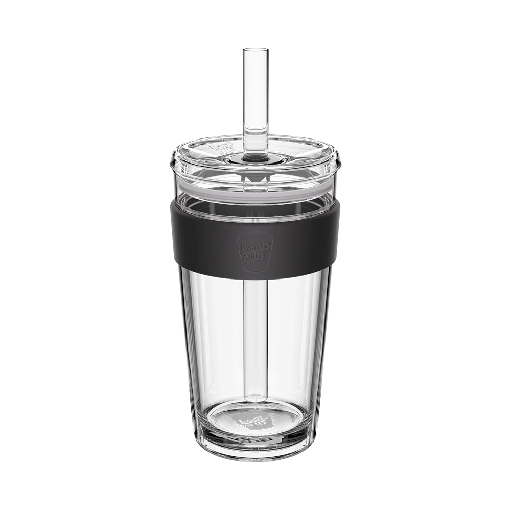 Large glass tumbler with black sleeve and straw on a white background