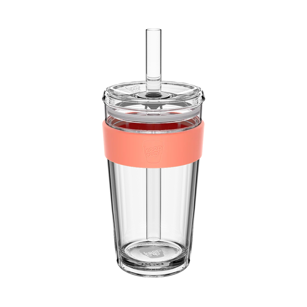 Clear glass tumbler with a coral-colored lid and straw on a white background