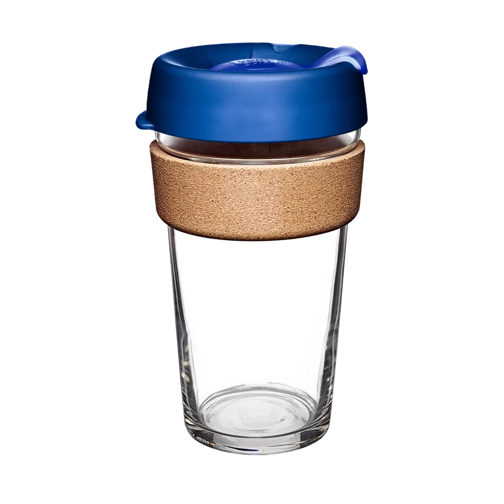 Clear glass reusable mug with a blue lid and cork sleeve on a white background