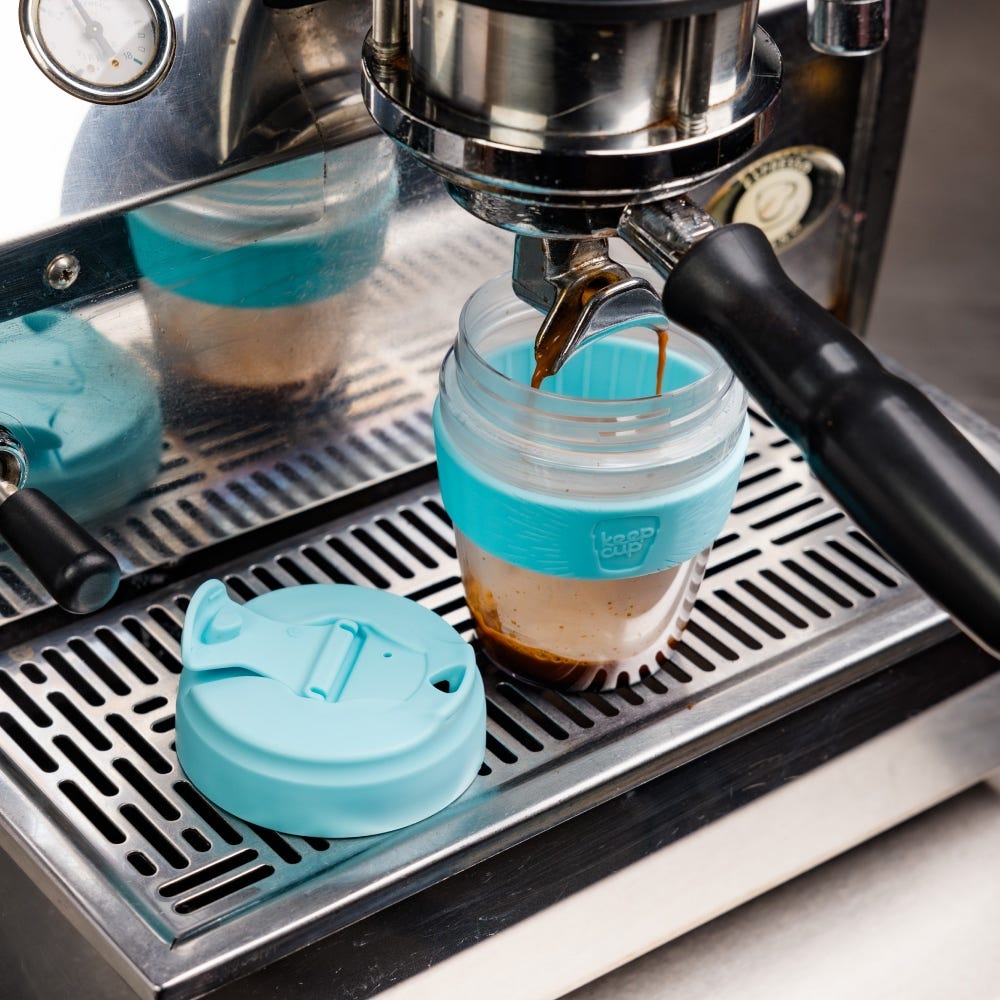 Espresso machine filling cloud blue commuter cup with lid beside