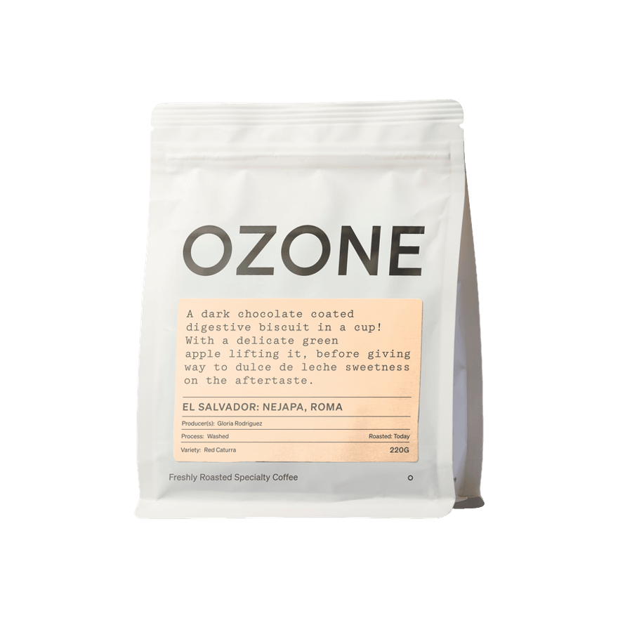 White 220g bag of Ozone freshly roasted specialty coffee, El Salvador Nejapa Roma, featuring tasting notes of dark chocolate coated digestive biscuit, green apple and dulce de leche, with Red Caturra variety and washed process details on a peach-coloured label.