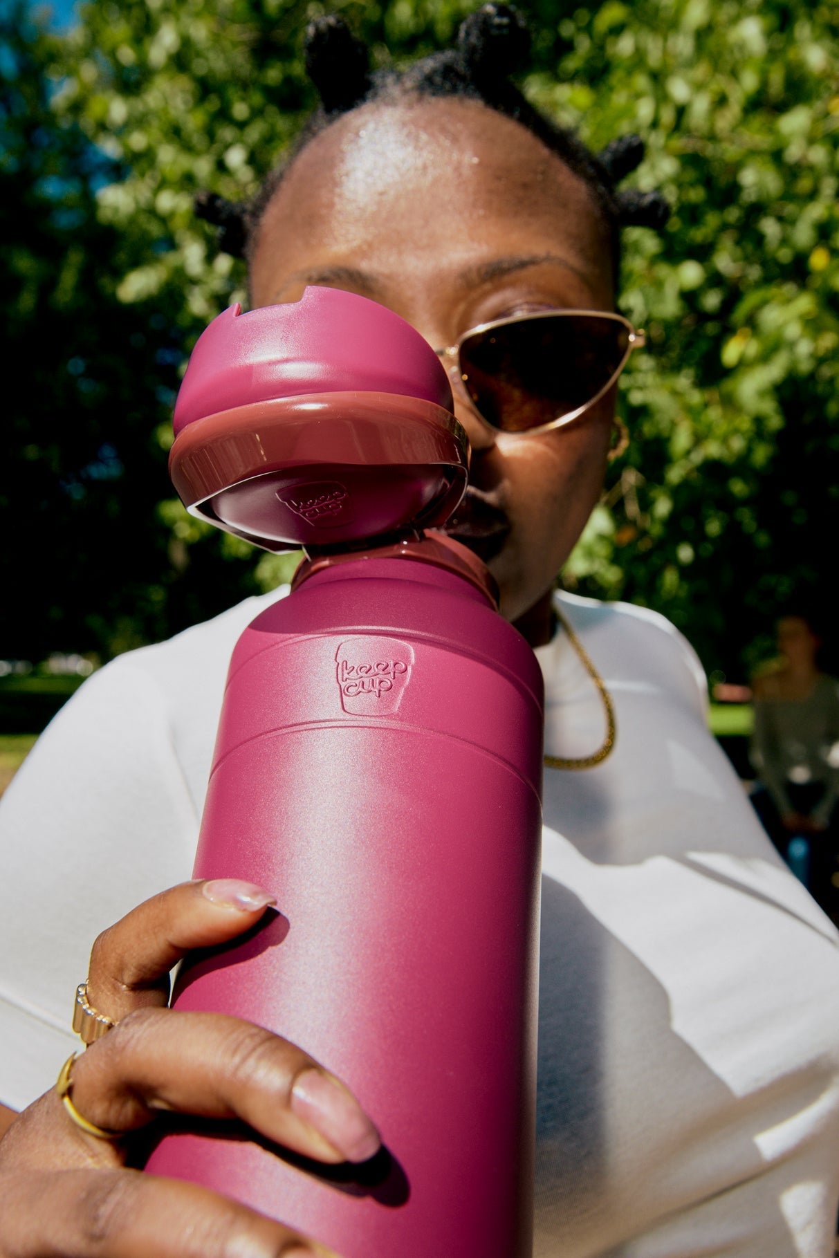 Person holding a mulberry water bottle with a blurred outdoor background