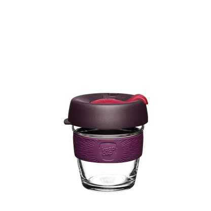 A KeepCup Brew XS reusable glass coffee cup with a dark purple silicone sleeve and a matching dark purple lid featuring a bright red plug shown on a plain white background