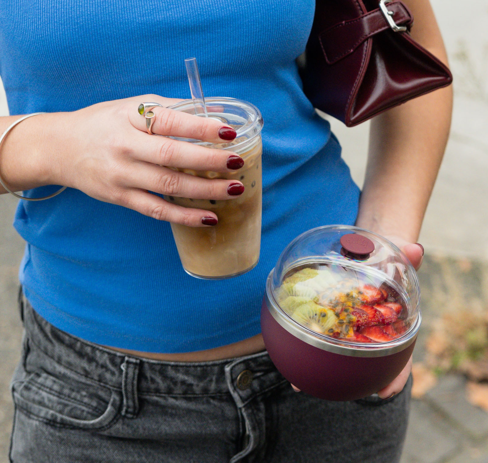 Person holding Cold Cup Original with iced coffee and Go Bowl Luxe in Mulberry with acai outdoors.