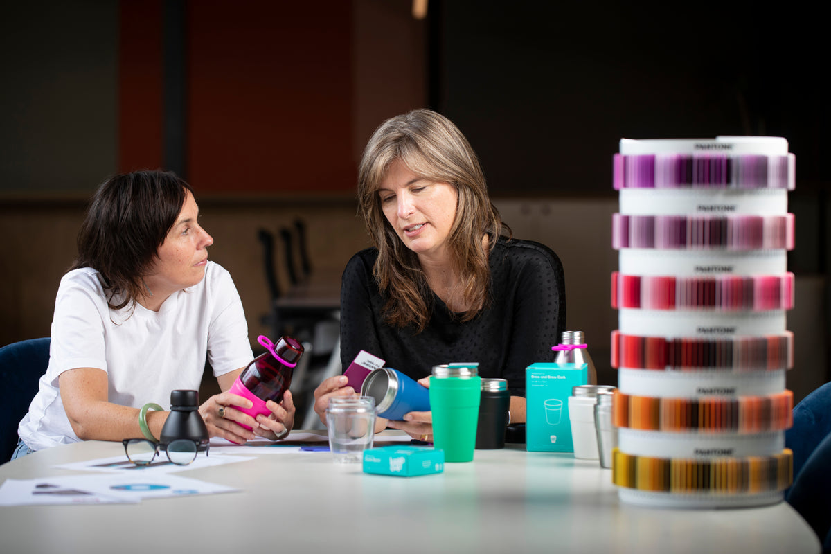 KeepCup founder Abigail Forsyth reviewing products at the head office next to stacks of pantone colour swatches.