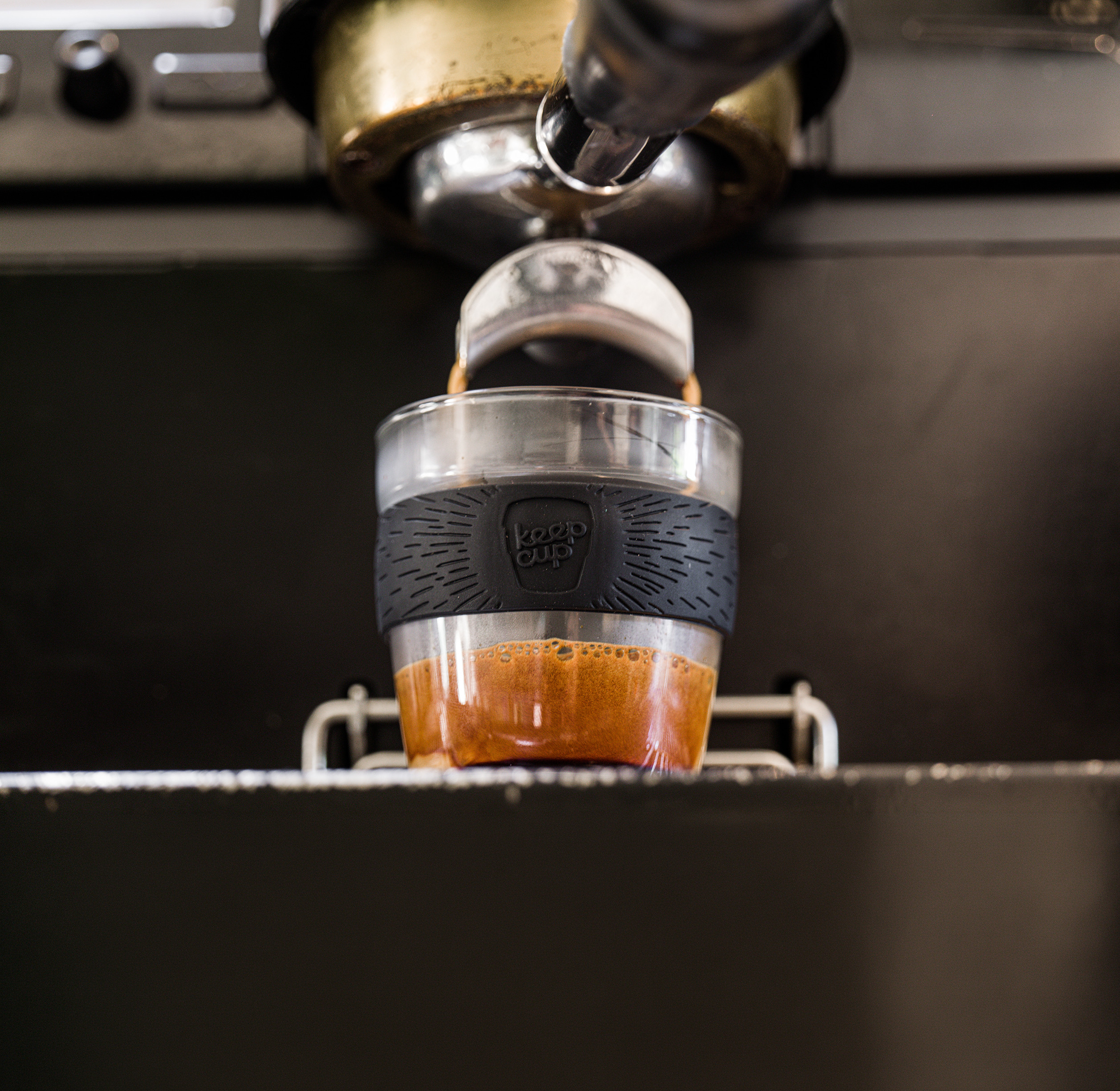 Espresso being poured into a clear glass cup with a black band.