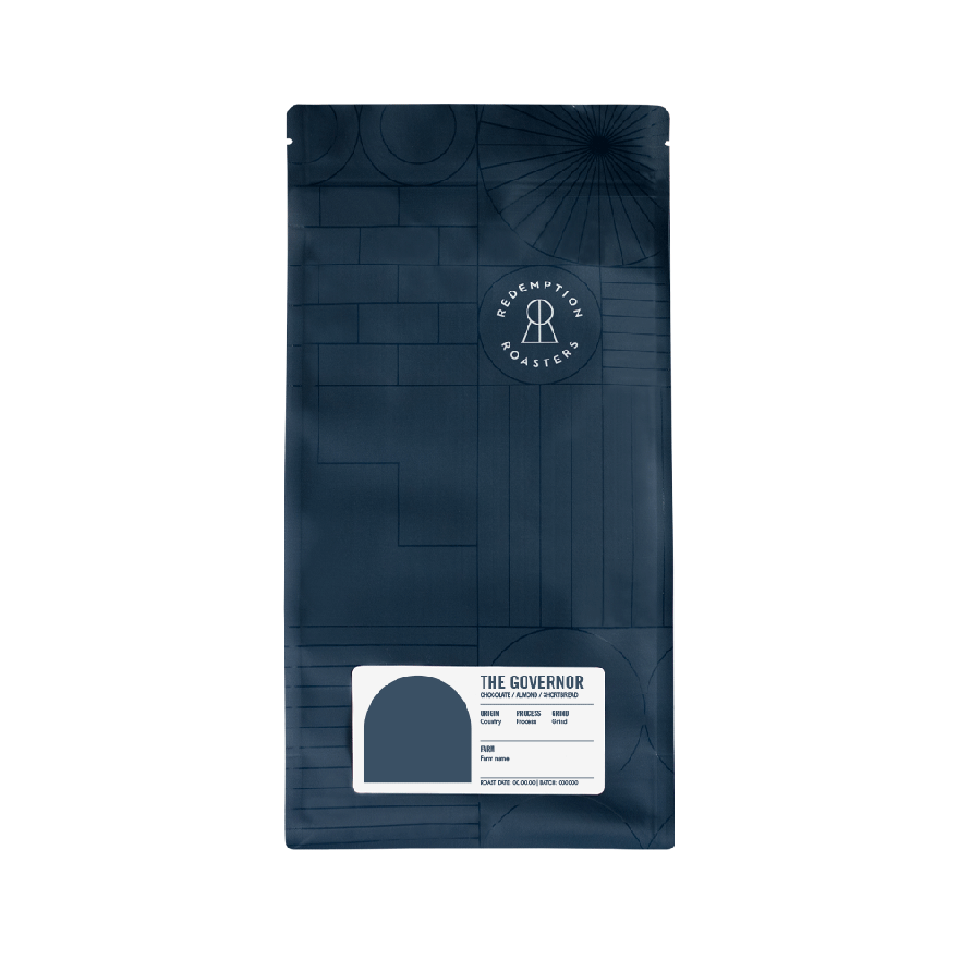 Dark navy blue 1kg coffee bag of The Governor blend by Redemption Roasters, featuring geometric patterns and the brand's circular logo, with a white label showing tasting notes of chocolate, almond and shortbread.