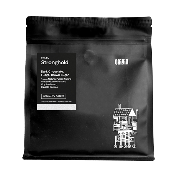 Black matte coffee bag for Origin Stronghold 250g Brazil speciality coffee, featuring tasting notes of dark chocolate, fudge and brown sugar, with a white illustrated design of a whimsical house structure in the bottom right corner.