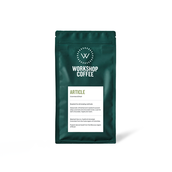 A dark teal stand-up pouch of Workshop Coffee Article 250g blend, featuring the brand's circular W logo and a white label detailing the Colombia and Brazil origin, tasting notes of deep caramels and chocolate, displayed against a plain white background.