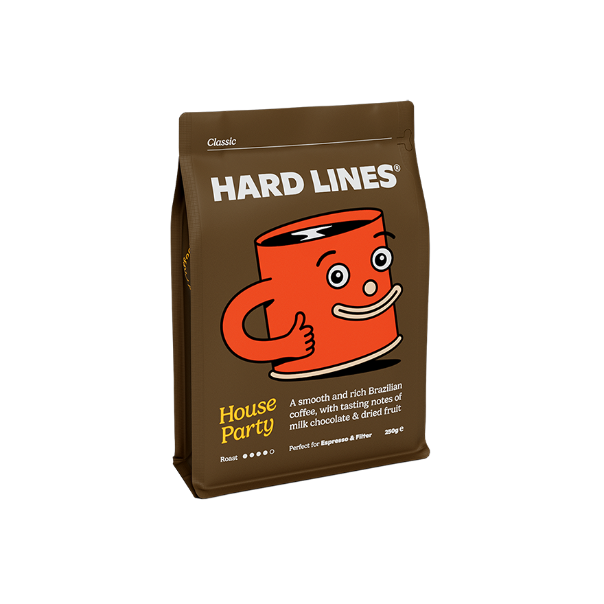 Brown coffee bag of Hard Lines House Party 250g Brazilian coffee, featuring a playful orange cartoon mug giving a thumbs up. The packaging notes tasting hints of milk chocolate and dried fruit, suitable for espresso and filter brewing.