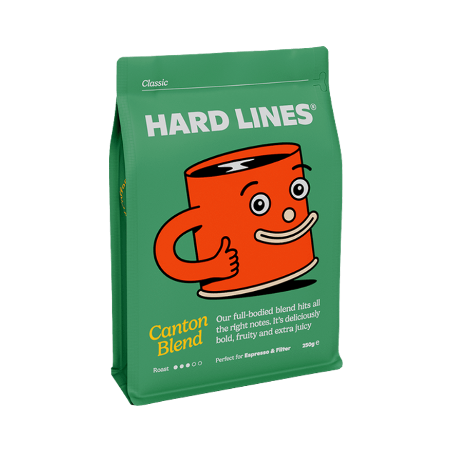 Green coffee bag of Hard Lines Canton Blend 250g featuring a cheerful orange mug character giving a thumbs up, labelled as a full-bodied blend perfect for espresso and filter.