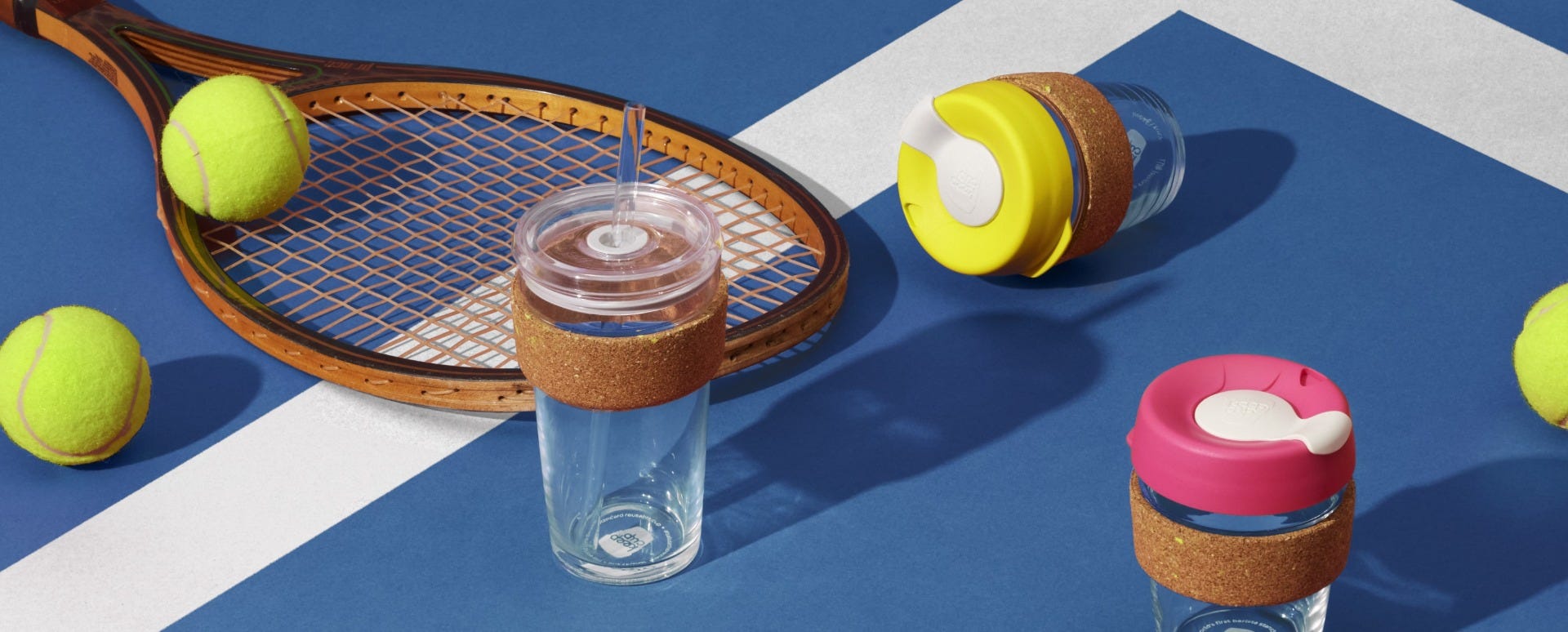 Woman holding KeepCup Sip & Chill Brew Cork Ace reusable glass cup on blue tennis court