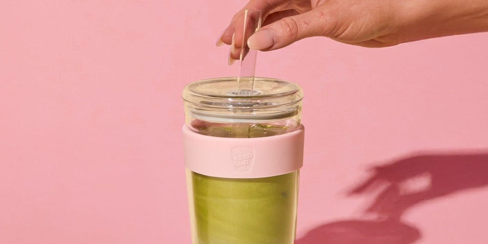 Person holding the straw of a KeepCup Longplay ColdCup in Pashmak Pink with iced matcha